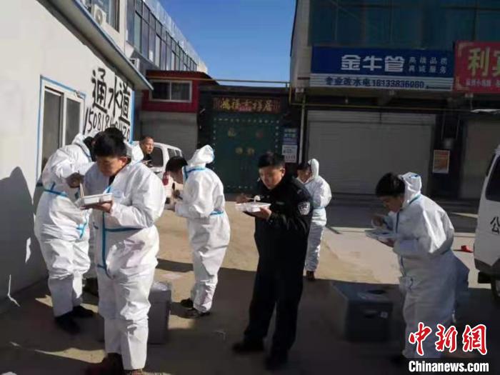 圖為藁城區(qū)增村鎮(zhèn)小果莊村疫情防控檢查站警員為暖和在陽光下吃飯?！堅露Y 攝