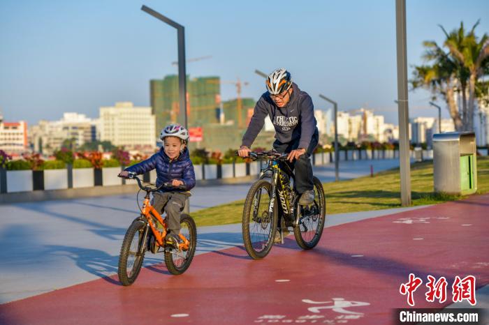 圖為一對(duì)父子騎行在剛剛開放不久的?？跒瞅T行道，樂享久違的陽光?！●樤骑w 攝