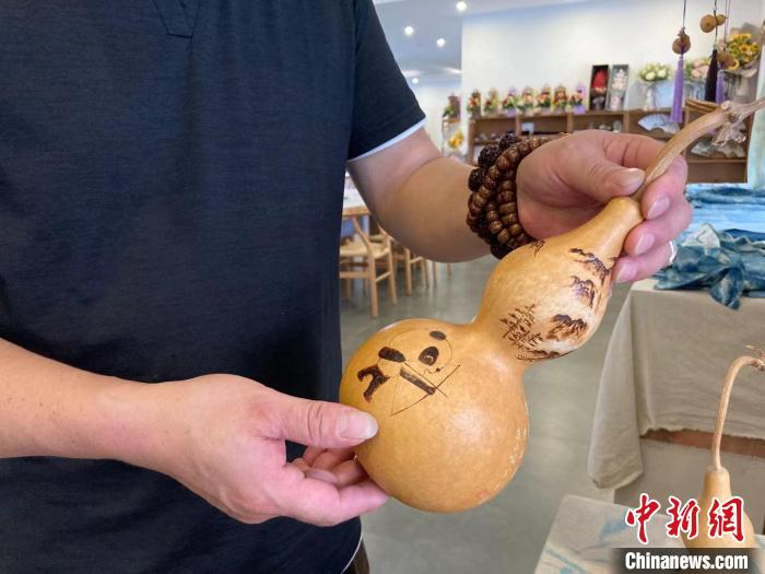 陶思俊展示自己創(chuàng)作的葫蘆烙畫?！￡愳o 攝