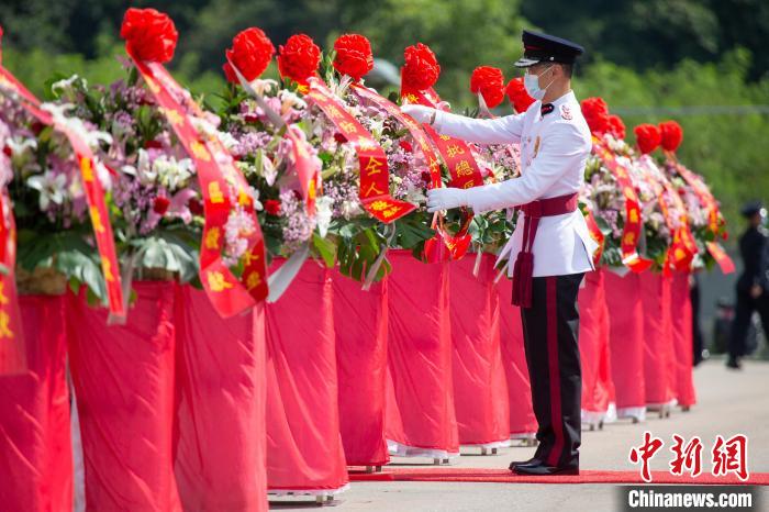 香港特區(qū)政府消防處處長梁偉雄在儀式上整理花籃上的挽帶。　政府新聞處供圖