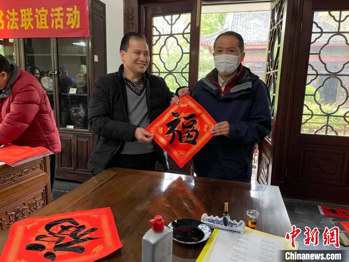 圖為一名日本人(右)展示其書寫的春聯(lián)?！×周?攝