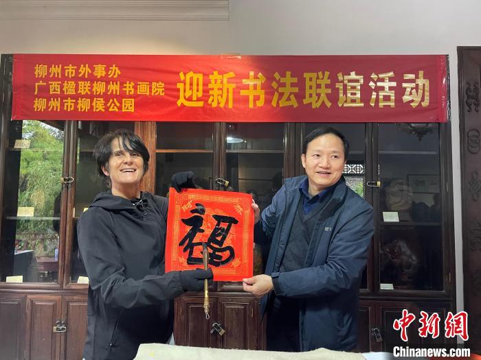 圖為一名英國人(左)展示其書寫的春聯(lián)?！×周?攝