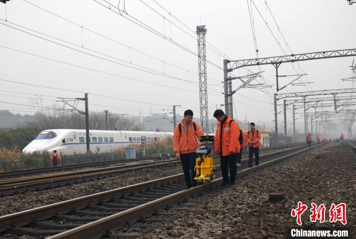 圖為探傷工使用鋼軌探傷儀對(duì)京九線廬山站區(qū)鋼軌進(jìn)行檢測(cè)，臨近的昌九城際線上一列動(dòng)車組呼嘯而過(guò)?！⊥鹾?攝