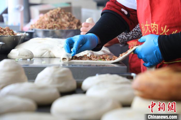 “火燒”師傅們將面劑拉長，抹上肉餡，再卷成陀螺狀，旋磨成型后壓平?！∴囆?攝