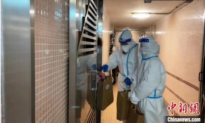 圖為吳學(xué)明和義工送抗疫物資到確診家庭手中?！∈茉L者供圖