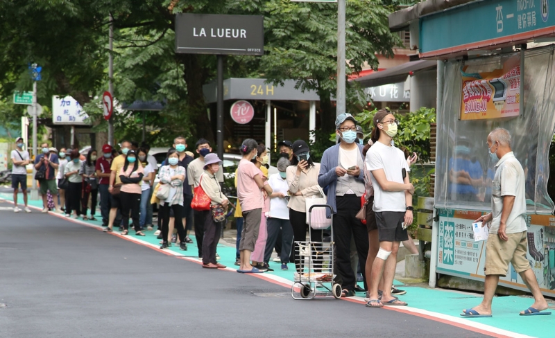 圖為民眾在藥局前大排長龍等待購買快篩試劑。（陳俊吉攝）