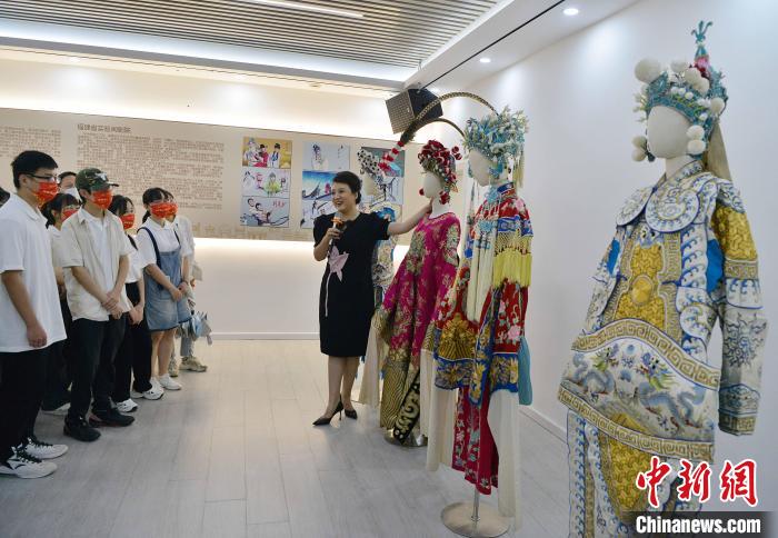 圖為福建省實(shí)驗(yàn)閩劇院工作人員為研學(xué)體驗(yàn)營學(xué)生介紹閩劇戲服?！埍?攝