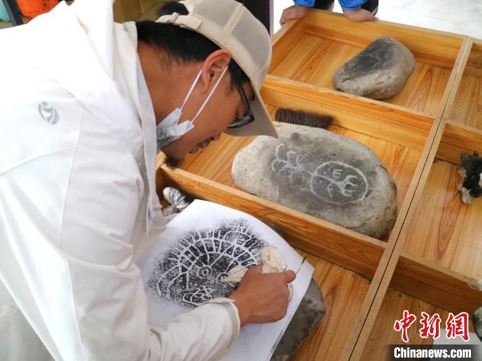 臺青用墨包為巖畫印記上色?！±钤?攝