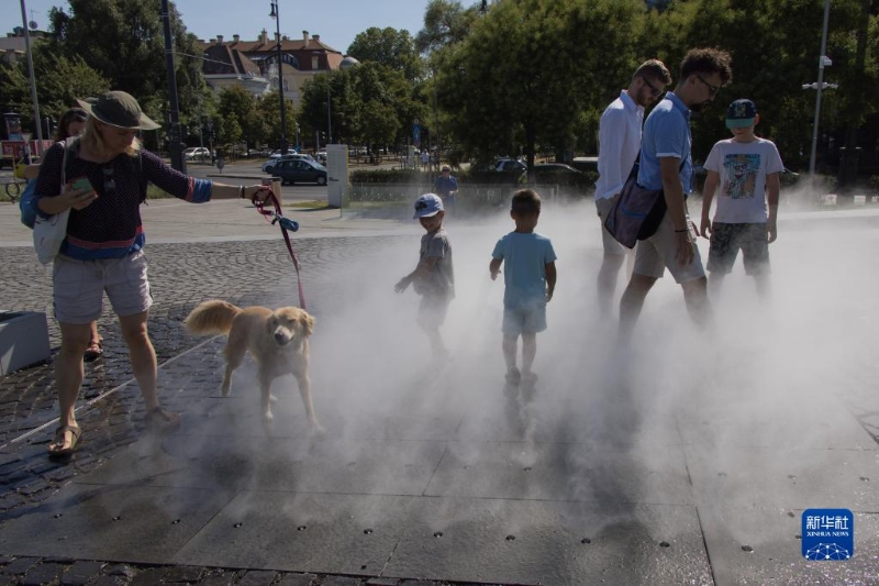 7月19日，在匈牙利布達佩斯，人們在一處公共加濕設施享受清涼的噴霧。（圖源：新華社）