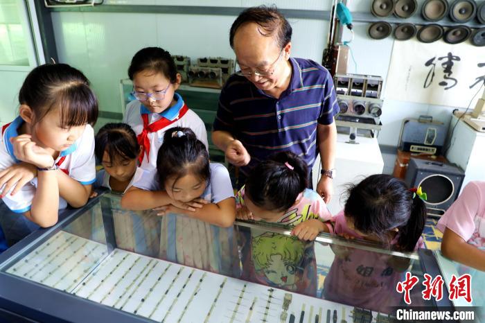 圖為肖光合正在給孩子們介紹收音機上的零件和電路原理。　沙飛 攝