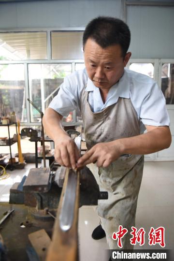 王二兵對(duì)燒制好的劍進(jìn)行修磨?！「哒挤?攝