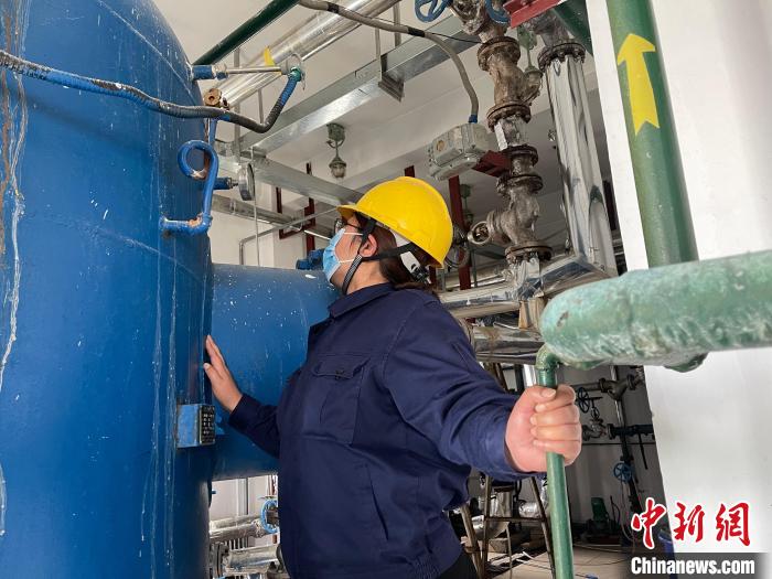 圖為王衛(wèi)玲認(rèn)真檢查鍋爐設(shè)備?！≈煊例?攝