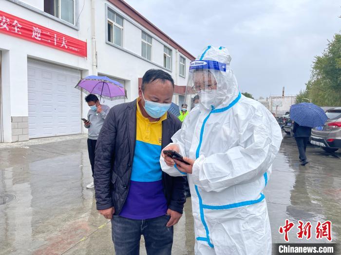 圖為王衛(wèi)玲(右)幫助做核酸的人員進(jìn)行個(gè)人信息登記?！≈煊例?攝