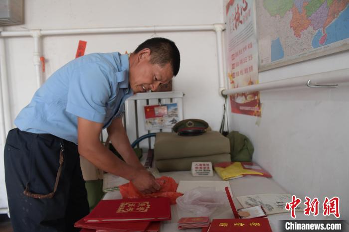 圖為謝建民整理當(dāng)兵時的榮譽證書?！『鷸|育 攝