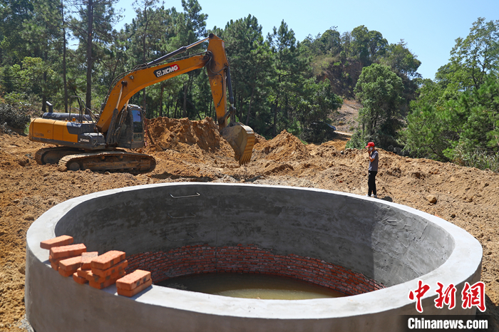 9月6日，在鄱陽湖畔的江西省九江市都昌縣多寶鄉(xiāng)林場，一臺挖掘機不停揮舞著“大臂”，為一口直徑5米、深8.5米的蓄水池進行場地平整，山泉水順著一根水管緩緩注入蓄水池內(nèi)。 <a target='_blank' href='/'>中新社</a>記者 劉占昆 攝