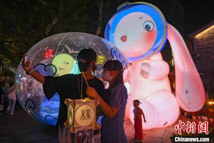 年輕人在燈市擺放著的“兔子燈”前留影?！°蟛?攝