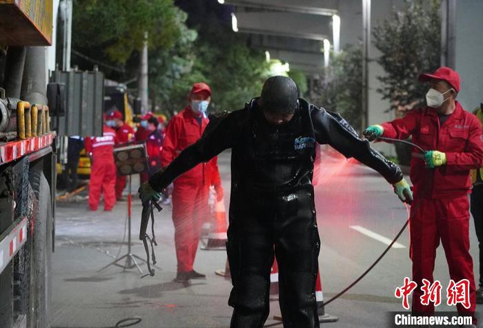 圖為“市政蛙人”出井后沖洗身上的工作服?！【琶赖┰?攝