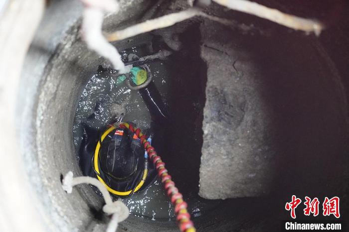 圖為“市政蛙人”穿著厚重的潛水服在狹小的污水井里作業(yè)?！【琶赖┰?攝