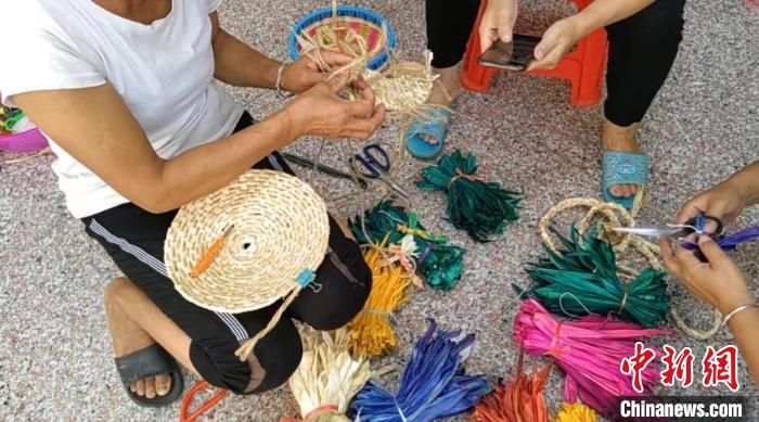 眾人正在用彩色玉米皮編織工藝品?！⒖÷?　攝