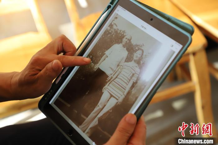 圖為廖奕斌查看老照片?！≈貞c榮昌區(qū)委臺辦供圖