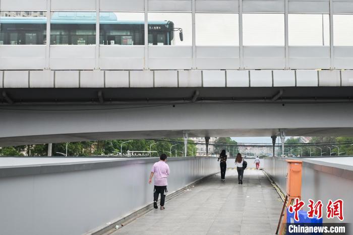 圖為市民走在天橋上，公交車從頭頂?shù)缆否傔^。　彭心怡 攝