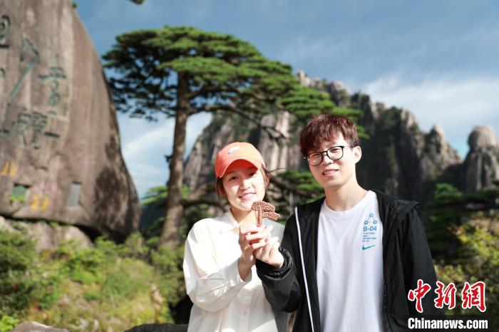 國(guó)慶假期游客拿著文創(chuàng)伴手禮在迎客松前合影 張濤 攝