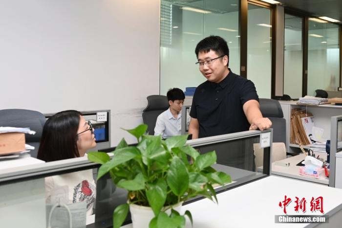 圖為9月23日，廣東廣州，余偉權(quán)(右一)和同事討論案件。 <a target='_blank' href='/'>中新社</a>記者 陳楚紅 攝