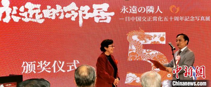 攝影展實(shí)行委員會中方代表劉莉生代表多元文化會館向日本前駐華大使阿南惟茂夫人阿南史代頒發(fā)獎狀?！≈鬓k方供圖