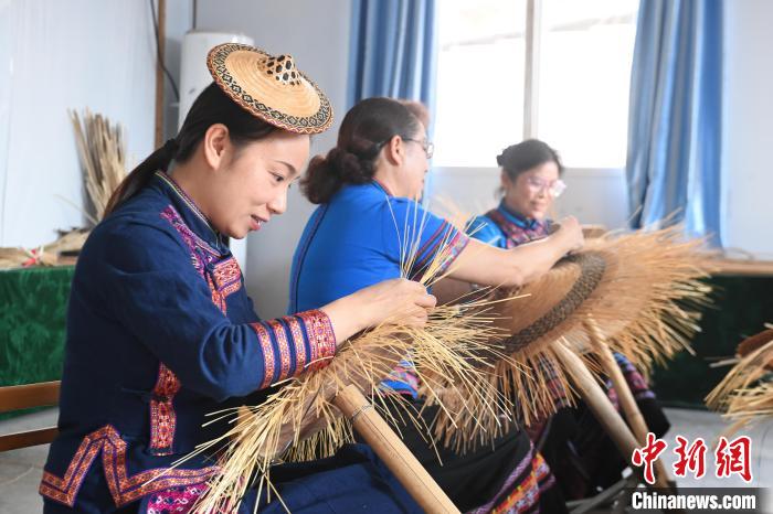 覃敏(左)和母親(中)在編織花竹帽。　王以照 攝