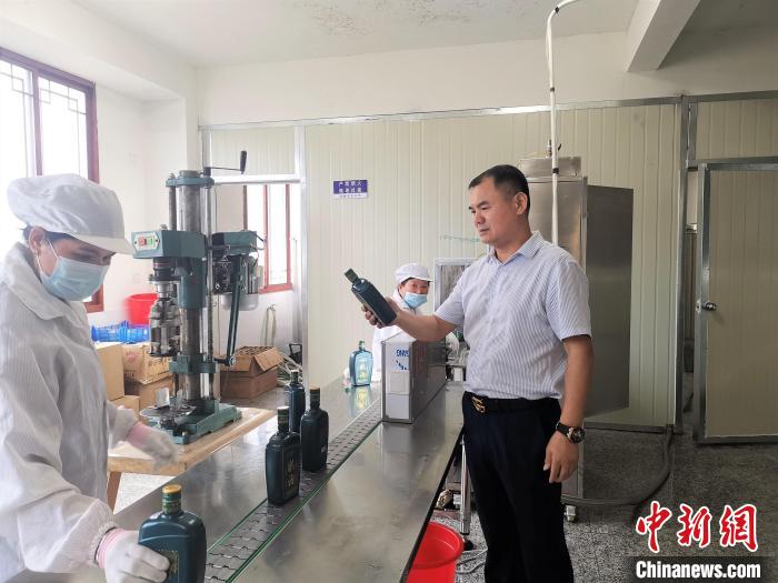 吳善遠(yuǎn)(右一)檢查黃酒包裝是否達(dá)標(biāo)?！∑聊峡h委組織部 供圖