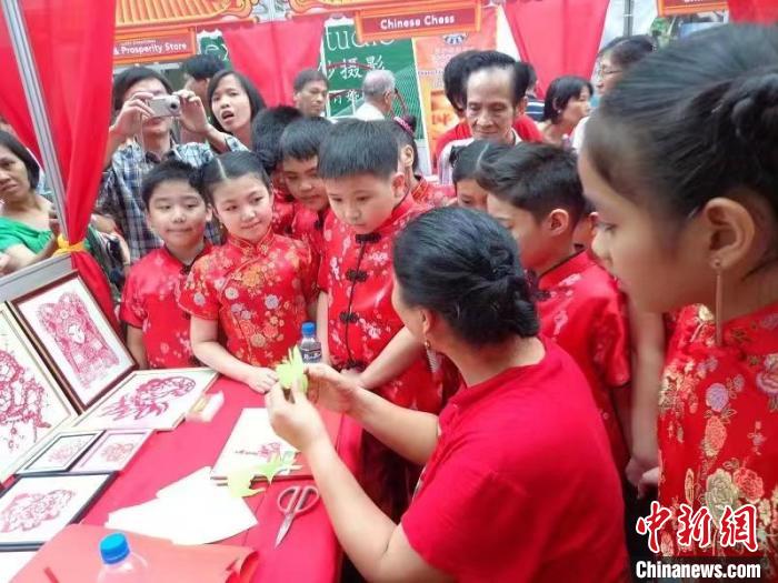 資料圖。2013年，正值中國新年，吳立喜在菲律賓馬尼拉市為菲律賓的華裔學生現(xiàn)場教學剪紙?！橇⑾补﹫D