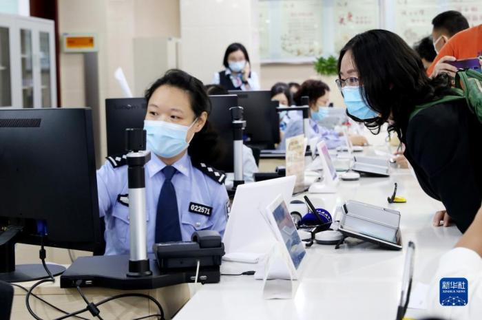 2020年10月14日，原籍浙江湖州的王秀麗(右)在上海市徐匯漕河涇社區(qū)事務(wù)受理服務(wù)中心公安綜合窗口辦理戶口遷移手續(xù)，成為享受上海市公安局會同浙江省公安廳共同推出的滬浙“跨省市戶口網(wǎng)上遷移”便民措施的第一人。新華社記者 方喆 攝