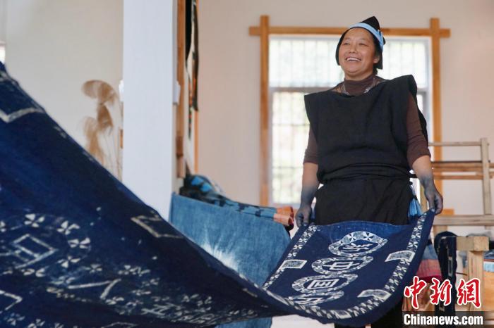 圖為黎鳳珍正在展示使用藍(lán)靛染工藝制作的條幅?！№f國政 攝