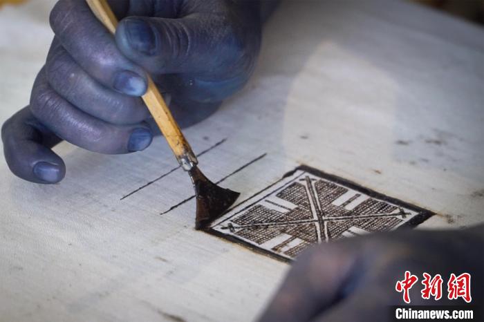 圖為黎鳳珍正手持著粘膏刀繪制“瑤王印”?！№f國政 攝