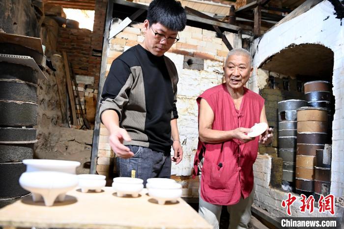 在窯口，林俊徒弟把已上釉的素坯傳給師傅?！埥鸫?攝