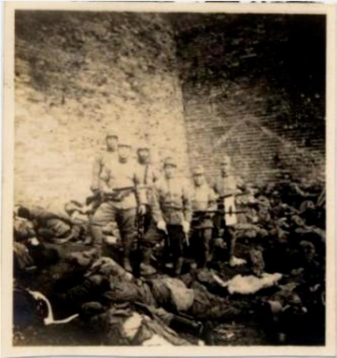 黑黑的城墻下面，是被日軍屠殺的累累尸首。日軍士兵手持步槍刺刀和日本軍旗，站在中國(guó)人的尸體旁炫耀著所謂的“武威”。圖源：侵華日軍南京大屠殺遇難同胞紀(jì)念館網(wǎng)站
