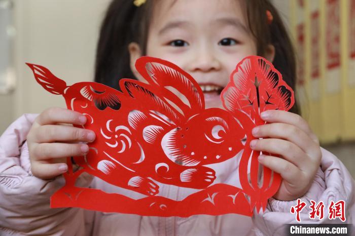 一名小朋友在展示兔年元素的剪紙作品?！±詈?攝