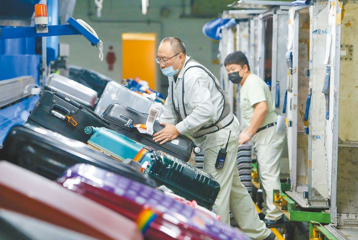 長榮航勤員工正在搬運成堆的旅客行李 長榮航勤員工正在搬運成堆的旅客行李