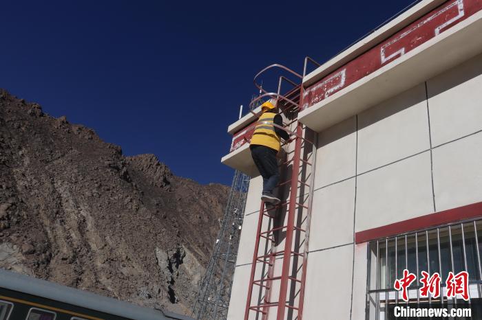 圖為馬智文利用古榮站站房爬梯進(jìn)行攀爬作業(yè)。　 馬生明 攝