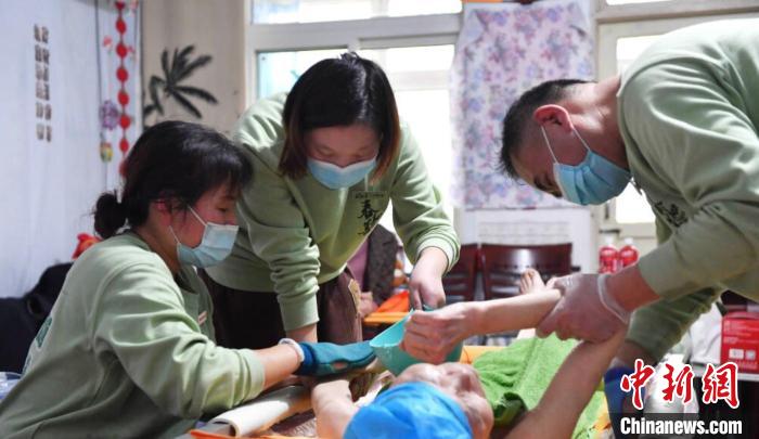 張慧和同事一起為老人進(jìn)行助浴服務(wù)?！∈茉L者供圖