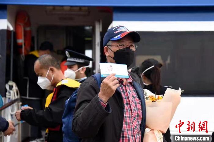 搭乘泉金航線的乘客展示手中的船票?！∪?攝