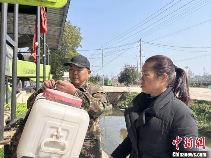 肖建青(右)和丈夫查看農(nóng)機情況?！⒚懒?　攝