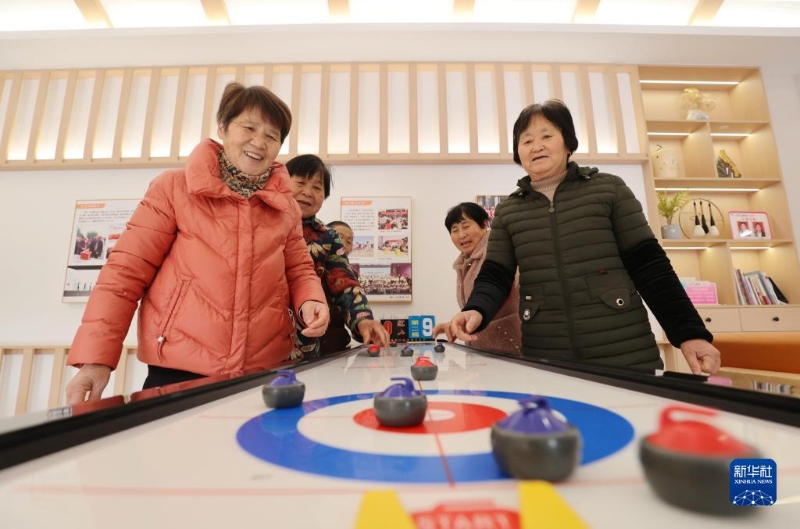 2月16日，在湖州市德清縣阜溪街道興山未來社區(qū)居家養(yǎng)老服務中心，社區(qū)老人在打“桌上冰壺球”。（圖源：新華社）