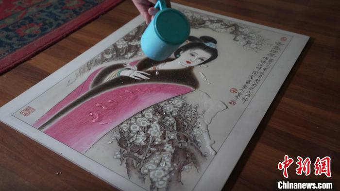 藺烈演示在板刻線畫(huà)作品上做防水試驗(yàn)，展示作品不僅防水還不掉色，濕水后還可用布擦拭?！∪诸?攝