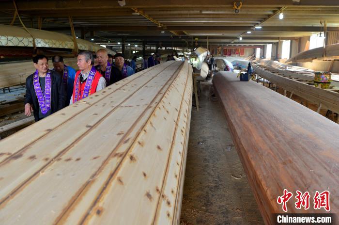 圖為“方莊龍舟制造技藝(閩侯縣)”傳承人方紹晃(左前)向參加儀式的兩岸嘉賓介紹龍舟制造技藝。　張斌 攝