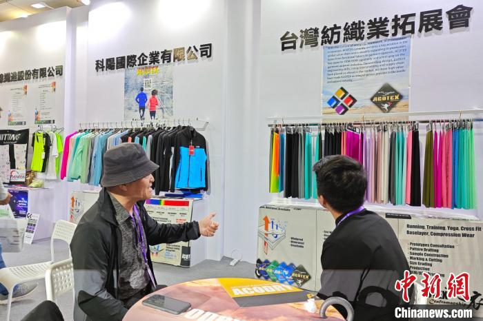 臺商邱鶴銘(左)在展位上介紹新研發(fā)的功能面料?！枪跇?biāo) 攝