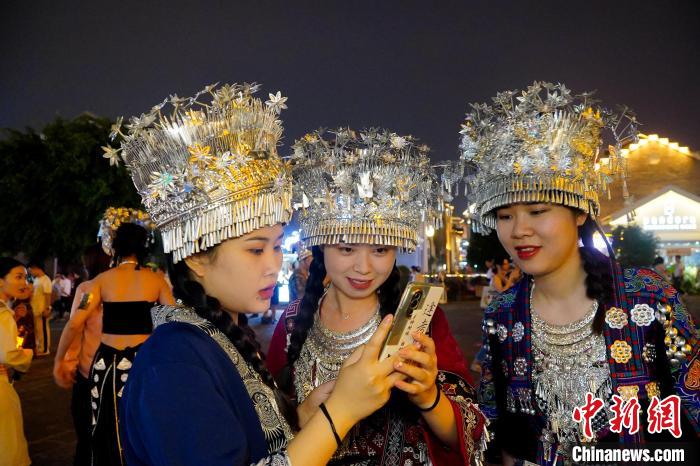 圖為身著苗族服飾的游客正在翻看照片?！№f國(guó)政 攝