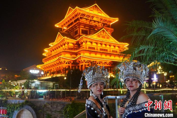 圖為身著苗族服飾的游客正在樓閣式建筑前“打卡”。　韋國(guó)政 攝