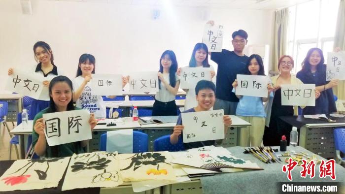 圖為留學(xué)生在展示書法作品?！±捉鹧?攝