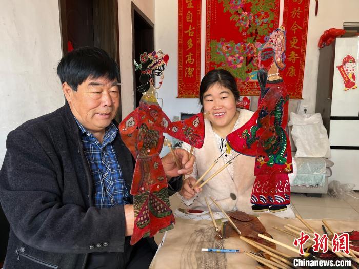 圖為馮克獻和女兒展示制作完成的皮影道具?！●R瑾 攝